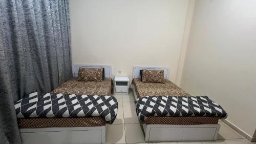 two beds in a small room with curtains at Luxury Twin Room Ajman One Tower in Ajman 