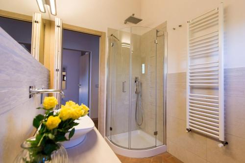 a bathroom with a shower and a vase of yellow flowers at Castellaccia contemporary country house in San Gimignano