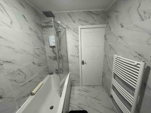 a white bathroom with a tub and a shower at The Ideal Beautiful 3-Bed House in Birmingham in Birmingham