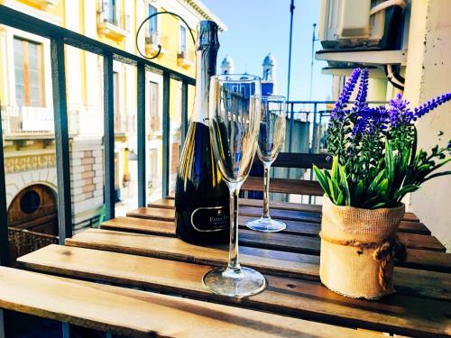 - une table avec 2 verres à vin et des fleurs sur le balcon dans l'établissement DUHOME apartment in the heart of Catania, à Catane