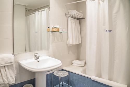 La salle de bains blanche est pourvue d'un lavabo et d'une baignoire. dans l'établissement Hotel Alda Castelao, à Vilagarcía de Arousa