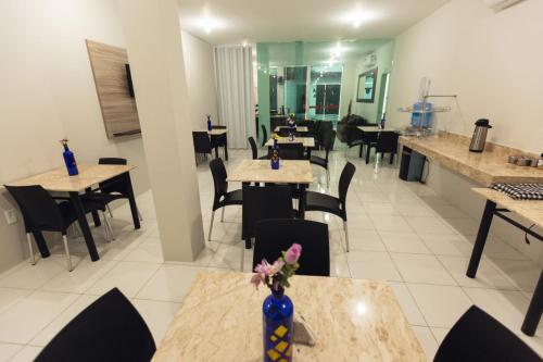 a restaurant with tables and chairs and a vase with flowers at Várzea HOTEL in Sobral