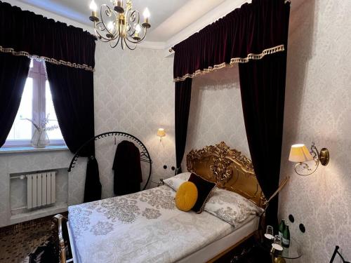 sypialnia z łóżkiem z fioletowymi zasłonami i żyrandolem w obiekcie Night o'clock Business and Spa Aparts w mieście Opole