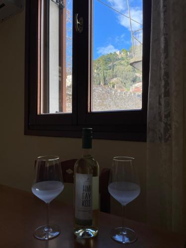 twee glazen wijn op een tafel met een raam bij Οι Φωλίτσες in Nafpaktos