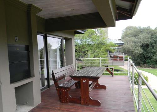 a wooden bench sitting on the porch of a house at Stonehill River Lodge by Dream Resorts in Buffeljagsrivier