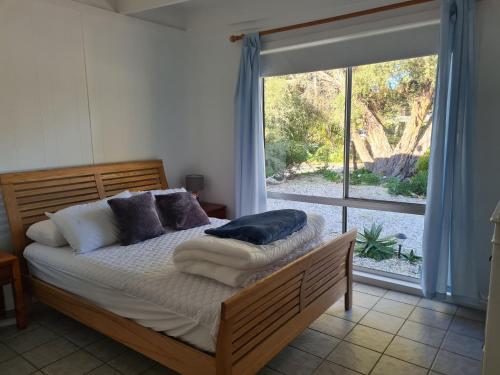 ein Schlafzimmer mit einem Bett und einem großen Fenster in der Unterkunft Kookaburra Lodge in Lock Sport