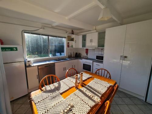 eine Küche mit einem Tisch und Stühlen sowie eine Küche mit einem Kühlschrank in der Unterkunft Kookaburra Lodge in Lock Sport