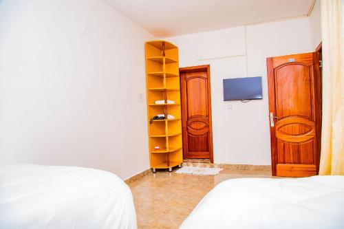 a bedroom with two beds and a tv and a closet at The Keza Hotel and Apartments in Kigali