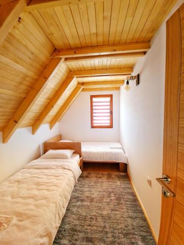 an attic bedroom with two beds and a window at Stara pruga Jaz 2 in Višegrad