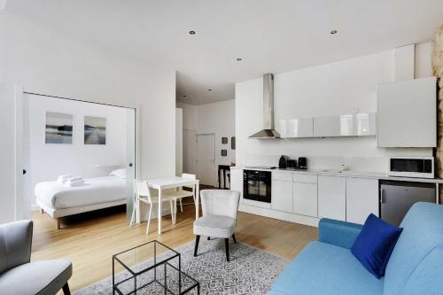 un salon avec un canapé bleu et une cuisine dans l'établissement Appart confortable -1BR 4P- Quartier Beaubourg, à Paris
