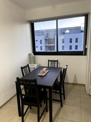 Chambre privée dans une colocation avec un balcon في مونبلييه: طاولة طعام مع كراسي ونافذة كبيرة