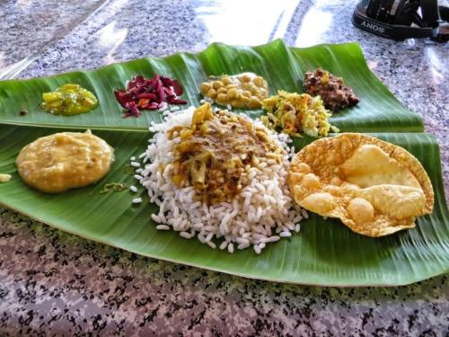 a plate of food on a banana leaf with rice at Munroe Meadows home in Munroe Island