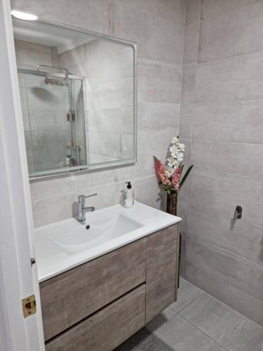 a bathroom with a sink and a mirror and flowers at Casa encantadora y acogedora en Roses in Roses