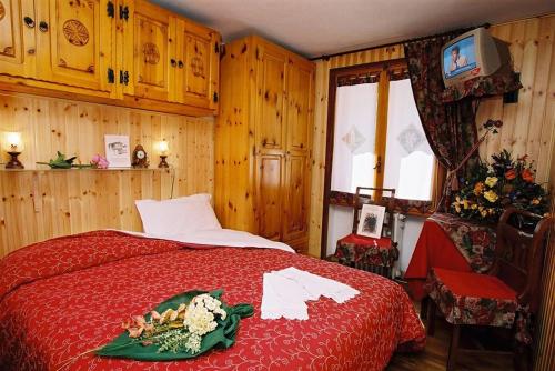 1 dormitorio con cama roja y TV en B&B Lepetitnid en Valtournenche