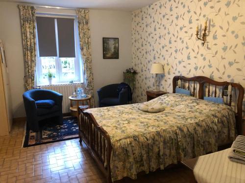 - une chambre avec un lit, deux chaises et une fenêtre dans l'établissement Le Voyageur, à Saint-Bonnet-Tronçais