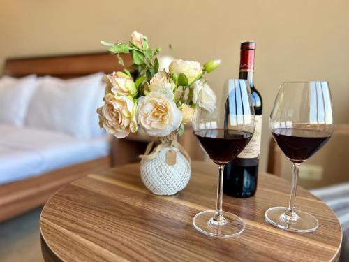 dois copos de vinho e um vaso de flores sobre uma mesa em Sky Magic view Hotel em Yerevan