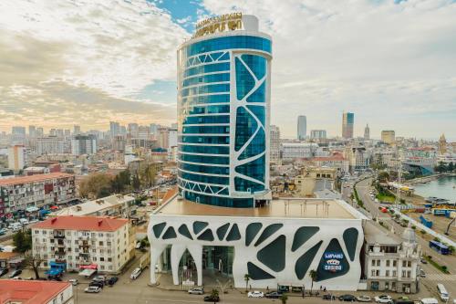 a tall blue building in front of a city at JRW Welmond Hotel in Batumi