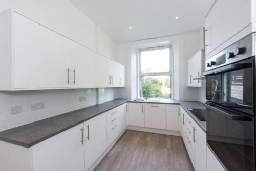 a white kitchen with white cabinets and a window at Spare Room Stay in Edinburgh