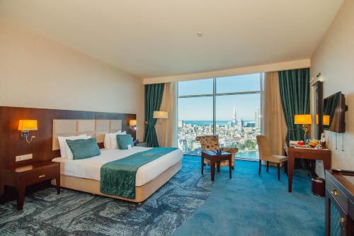 um quarto de hotel com uma cama grande e uma secretária em JRW Welmond Hotel em Batumi