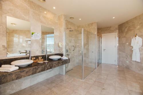 a bathroom with a glass shower and a sink at JRW Welmond Hotel in Batumi