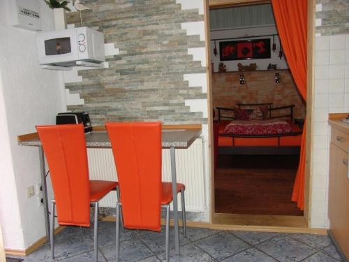 Wohnung in LübbenauSpreewald mit Garten, Terrasse und Grill في لوبنو: مطبخ مع كراسي بار برتقالي وغرفة نوم