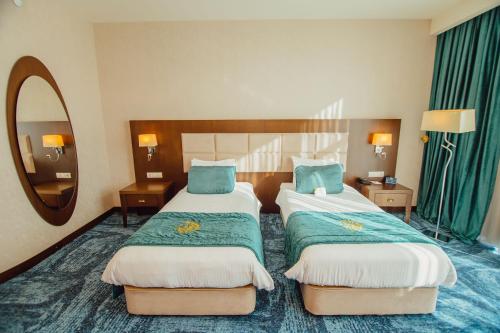 a hotel room with two beds and a mirror at JRW Welmond Hotel in Batumi