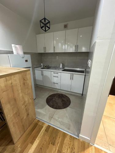 a kitchen with white cabinets and a rug on the floor at Apartment Sun & Moon in Sarajevo
