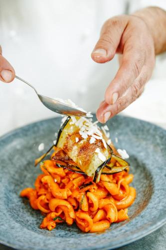 a person eating pasta on a plate with a fork at La Plage Resort in Taormina