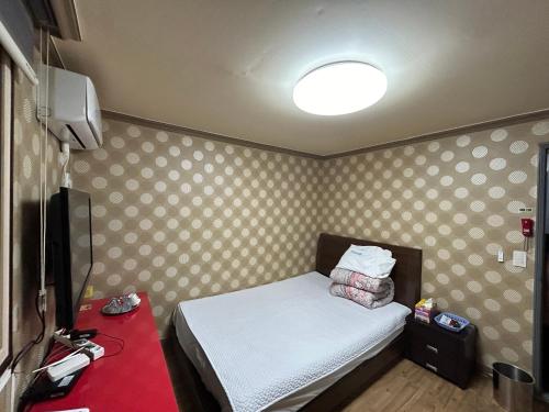 um pequeno quarto com uma cama e uma televisão em Sang Il Jang em Mokpo