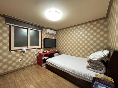 um pequeno quarto com uma cama e uma televisão em Sang Il Jang em Mokpo