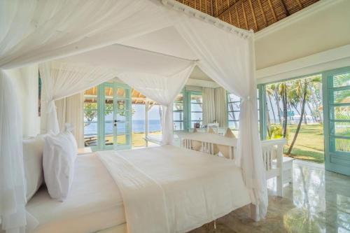 a bedroom with a white bed and a table at Scuba Seraya Resort in Tulamben