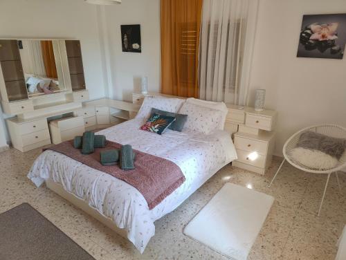 a bedroom with a white bed and a chair at A & A Holiday House in Larnaka