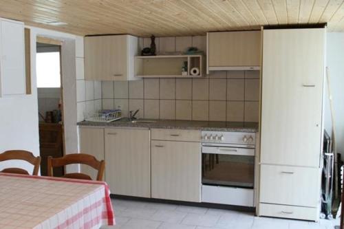 eine Küche mit weißen Schränken, einem Herd und einem Tisch in der Unterkunft Bambi in Wirzweli