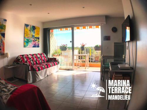 een woonkamer met een bank en een glazen schuifdeur bij Marina Terrace in Mandelieu-la-Napoule