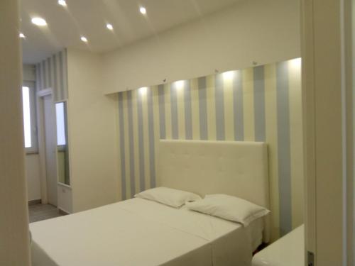a bedroom with a white bed and a striped wall at Maison De luxe in Pompei