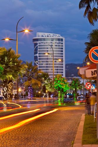 a city street at night with a tall building at JRW Welmond Hotel in Batumi