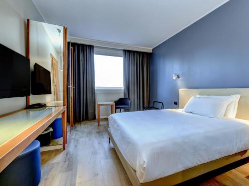 クアルト・ダルティーノにあるB&B Hotel Quarto d'Altinoの大きなベッドとデスクが備わるホテルルームです。
