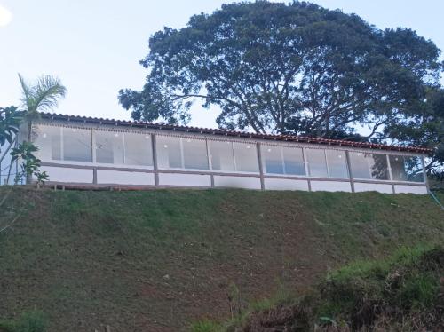 a house on a hill with a tree in the background at Sítio Werly in Domingos Martins