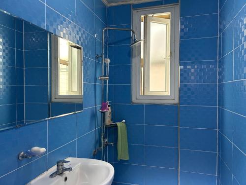 La salle de bains est pourvue de carrelage bleu, d'un lavabo et d'un miroir. dans l'établissement Swiss Motel, à Mokpo