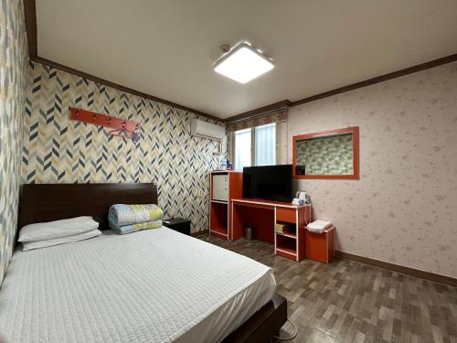 木浦的住宿－Swiss Motel，一间卧室配有一张床、一张书桌和一台电视