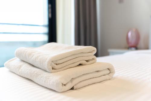 a stack of towels sitting on top of a bed at Beautifully furnished 3BDR in Al Sidir Greens in Dubai