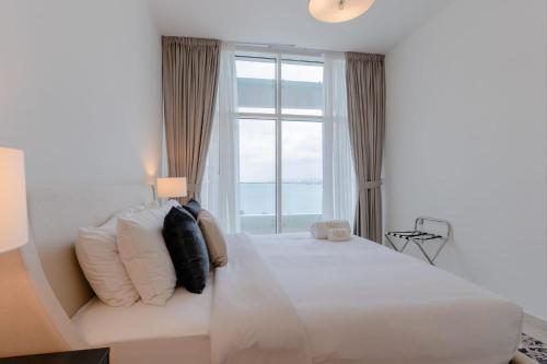 um quarto com uma grande cama branca e uma janela em LUXFolio Retreats Incredible Views Private Beach em Dubai