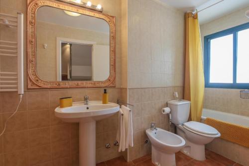 een badkamer met een wastafel, een toilet en een spiegel bij Magallanes in El Portil
