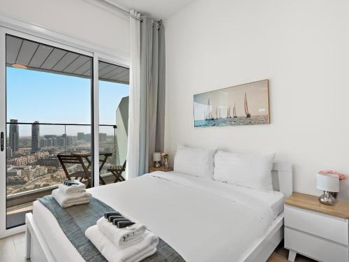 ein Schlafzimmer mit einem weißen Bett und einem großen Fenster in der Unterkunft Spacious Studio With A Sofa Bed In JVC in Dubai