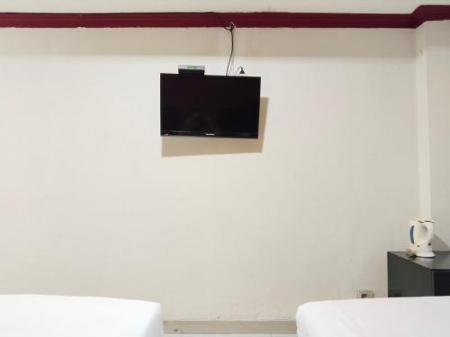 a flat screen tv hanging on a white wall at Metro Hotel Bekasi powered by Cocotel in Bekasi