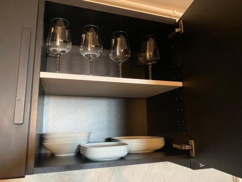 um armário com copos de vinho e pratos em Evan cozy flat with indoor pool Militari Residence em Roşu