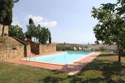 a swimming pool in a yard with a stone wall at Agriturismo Colle Verde in Castelfalfi