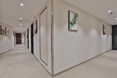 a hallway with white walls and paintings on the walls at Hotel Elements Surat in Surat