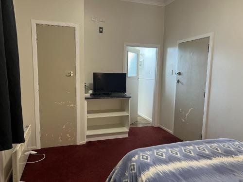 a room with a bedroom with a bed and a television at Oasis Motel - waiouru in Waiouru