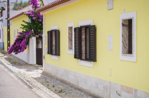 a yellow building with brown shutters on a street at Oliveira Country House in Figueira e Barros